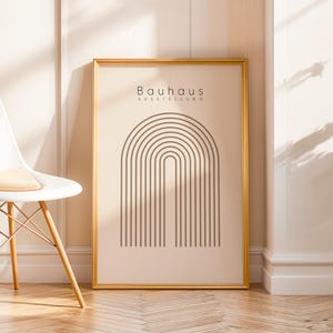Könnte beinhalten: Ein gerahmter Kunstdruck mit minimalistischem Design. Er zeigt eine Reihe von gebogenen, parallelen Linien in Dunkelbraun, die einen Bogen bilden. Der Druck hat einen beigefarbenen Hintergrund mit dem Text "Bauhaus Ausstellung". Der Rahmen ist goldfarben.