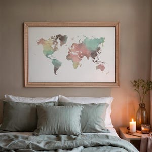 Può includere: Una stampa artistica incorniciata di una mappa del mondo con un design ad acquerello nei toni del rosa, verde e marrone. La mappa è esposta sopra un letto con cuscini e biancheria da letto verde salvia. Una candela accesa e un vaso con verde sono su un comodino.