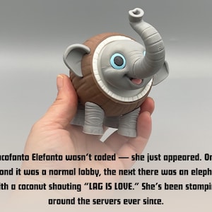 K&ouml;nnte beinhalten: Eine graue Elefantenfigur mit einem braunen, kokosnussartig texturierten K&ouml;rper, gro&szlig;en Ohren und blauen Augen. Der Text lautet: Cocofanto Elefanto wasn't coded &mdash; she just appeared. One second it was a normal lobby, the next there was an elephant with a coconut shouting &ldquo;LAG IS LOVE.&rdquo; She's been stomping around the servers ever since.