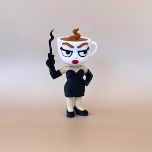 May include: A figurine shaped like a white coffee cup with a brown swirl on top, featuring a face with arched eyebrows, red lips, and long eyelashes. The figure wears a black strapless dress, black gloves, and black shoes, holding a black wand.