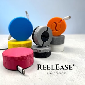 May include: A selection of brightly coloured cable tidies in blue, orange, pink, yellow, grey, and black. Each tidy has a circular or cylindrical form with a cable emerging. The text "REEL EASE" and "JUNGLE FORGE 3D" are displayed.