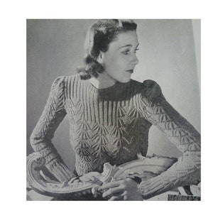 Puede incluir: Una foto en blanco y negro de una mujer con un suéter de punto con un patrón geométrico. El suéter tiene un cuello redondo y mangas largas.