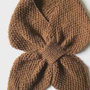 May include: A brown, hand-knitted scarf with a textured appearance. The scarf is folded and crossed at the centre, creating a layered effect. The knitted pattern is visible throughout the scarf.