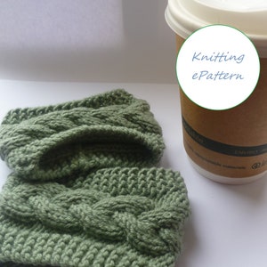 May include: A green knitted coffee cozy with a cable knit pattern. The cozy is next to a brown paper cup with a white lid. The cup has a white circle with the text "Knitting ePattern" on it.