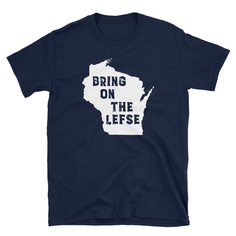 May include: Navy blue t-shirt featuring a white outline of the state of Wisconsin with the words "BRING ON THE LEFSE" printed inside the state outline. The shirt is made of a soft material.