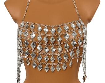 May include: Silver-toned chainmail top with a halter neck design. The top features rows of diamond-shaped, clear, sparkling embellishments. The chainmail cascades down the torso, creating a shimmering effect. This piece is a statement accessory.