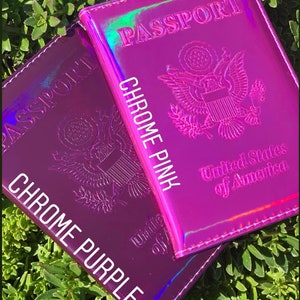May include: Two passport covers, one in chrome purple and one in chrome pink. Both covers have the words "PASSPORT" and "United States of America" printed on them.