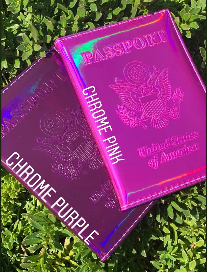 May include: Two passport covers, one in chrome purple and one in chrome pink. Both covers have the words "PASSPORT" and "United States of America" printed on them.