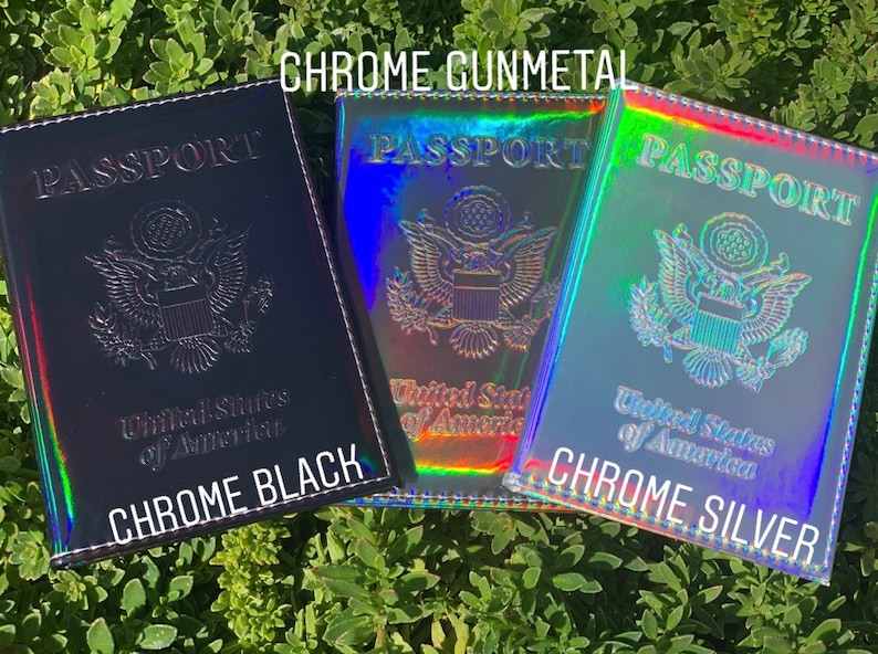 May include: Three passport covers in different colors: chrome black, chrome gunmetal, and chrome silver. Each cover has the words "PASSPORT" and "United States of America" printed on the front.