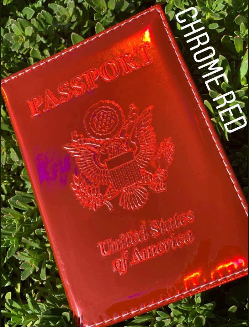 May include: A red passport holder with a chrome finish. The holder has the words "PASSPORT" and "United States of America" embossed on the front. The holder is labeled "CHROME RED".