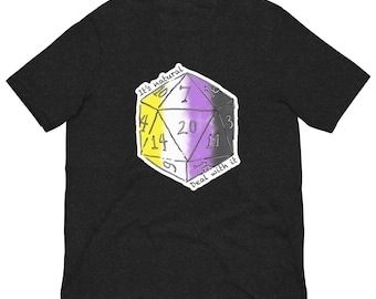 May include: Dark gray t-shirt featuring a graphic of a 20-sided die with the non-binary pride flag colors. The die has the text "It's natural" and "Deal with it". The shirt is a short-sleeved crew neck.
