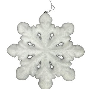 以下が含まれることがあります： 銀色の紐が付いた、白くキラキラ光る雪の結晶のオーナメント。 雪の結晶は、8つのポイントと中心的なパターンを持つ、詳細でテクスチャ加工されたデザインです。 ホリデーデコレーションに最適です。
