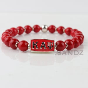 Kappa Alpha Psi Fraternity Stretch Bead Bracelet: KAΨ center bead paired with silver tone & crimson coral beads. Perfect gift for a Nupe!