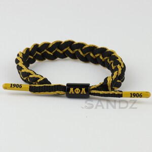 Iota Phi Theta Fraternity Charcoal Brown Gold Paracord Bracelet. Center Piece with 1963 Embossed End Caps. Adjustable 6.5 to 8.5