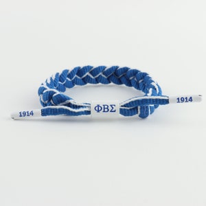 Phi Beta Sigma Fraternity: Royal Blue & White paracord bracelet. ΦBΣ center piece with 1914 embossed end caps. Adjustable 6.5&quot; to 8.5&quot;