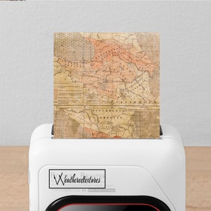 Peut inclure: Une imprimante blanche avec une ligne rouge en bas. L'imprimante imprime une carte vintage de la r&eacute;gion du Caucase. La carte est dans des tons de brun, orange et jaune. L'imprimante porte un logo qui dit "Rock Printer by Weatheredtextures High Resolution Print Head Memobird G4 2hrs Fast Charge".