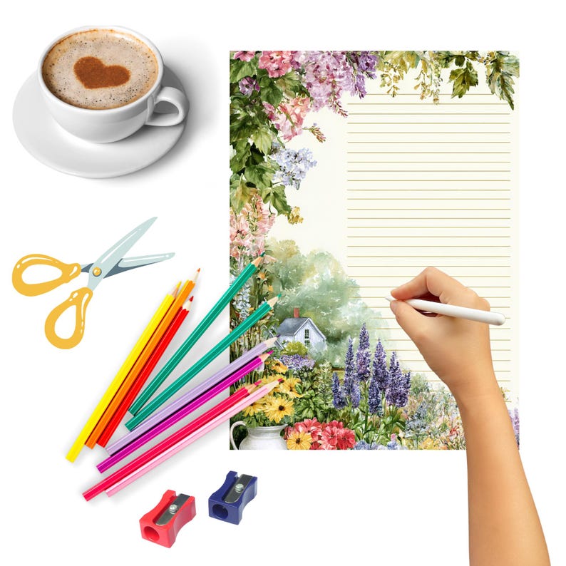 May include: A cup of coffee with a heart-shaped design in the foam, a pair of scissors, colored pencils, pencil sharpeners, and a floral-themed notepad. The notepad has a watercolor painting of a garden scene.