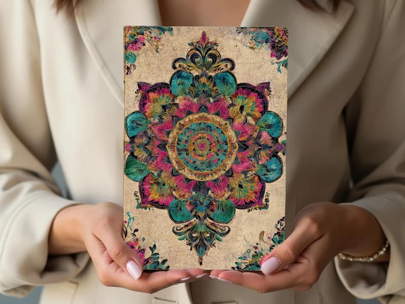 K&ouml;nnte beinhalten: Ein rechteckiges Notizbuch mit einem detaillierten Mandala-Design. Das Mandala weist eine lebendige Farbpalette auf, darunter T&uuml;rkis, Rosa und Gold, vor einem beigefarbenen Hintergrund. Florale Akzente schm&uuml;cken die Ecken. Das Notizbuch wird von einer Person gehalten.