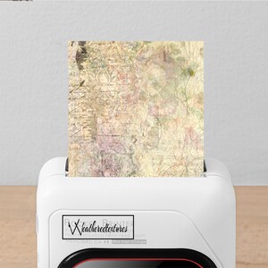 K&ouml;nnte beinhalten: Ein wei&szlig;er Drucker mit einem roten Akzent an der Unterseite. Der Drucker druckt ein Blatt Papier mit einem Vintage-Blumenmuster. Der Drucker hat ein Logo mit der Aufschrift "Weatherredtextures" und "Memobird G4" mit einem Symbol f&uuml;r schnelles Laden.