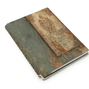 May include: A rectangular journal with a distressed, textured cover. The cover is divided into two sections: a teal-colored section and a brown section with a floral design. The journal is open, revealing white pages.