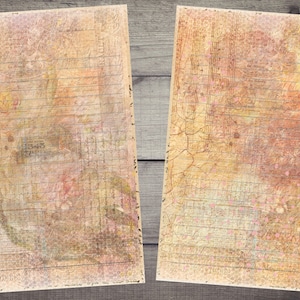 Op de afbeelding: Twee vellen vintage-papier met een verweerde, textuurrijke uitstraling. Het papier heeft een lichtbruine achtergrond met vervaagde roze en gele accenten. Het papier heeft een rasterpatroon en lijnen om op te schrijven.