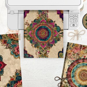 K&ouml;nnte beinhalten: Gedruckte Kunstwerke mit einem zentralen Mandala-Design in T&uuml;rkis, Rosa und Goldt&ouml;nen. Das Kunstwerk ist von floralen Mustern umgeben und wird zusammen mit anderen Drucken, einer Sukkulente und einem Drucker pr&auml;sentiert.