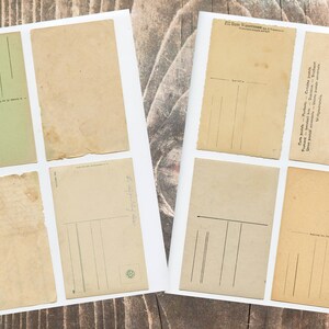 May include: Eight vintage postcards with blank spaces for writing messages. The postcards are on a wooden surface.