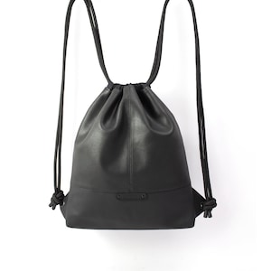 Könnte beinhalten: Ein schwarzer Leder-Rucksack mit Kordelzug und verstellbaren Trägern.