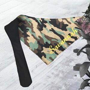 May include: A green, brown, and tan camouflage bandana with a black adjustable strap and the name "Savannah" embroidered in yellow.