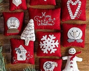 May include: A collection of 12 felt Christmas ornaments in various designs, including a deer, a snowflake, a snowman, a Christmas tree, a house, a candy cane, a snow globe, a poinsettia, and a gingerbread man. The ornaments are all red and white and have a Nordic theme.