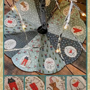 May include: A round, quilted Christmas tree skirt with a patchwork design in shades of blue, gray, and green. The skirt features embroidered appliqués with holiday-themed images and text, including houses, gifts, and a cat wearing a hat.