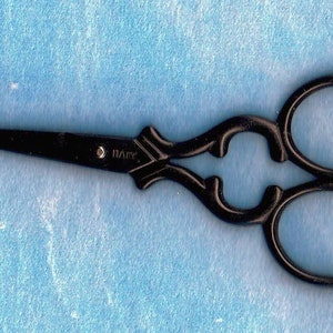May include: Black decorative scissors with an ornate design and the word "DAPY" engraved on the handle.