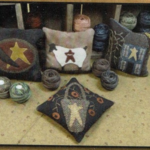 May include: Five handmade throw pillows with various designs. The pillows are made of fabric and feature a variety of colors, including brown, white, and blue. The pillows are arranged on a brown surface with balls of yarn.
