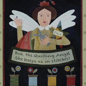 Peut inclure: Une appliqué en feutre fantaisiste d'un ange avec des ailes, tenant des ciseaux et un morceau de tissu. L'ange porte une robe rouge et verte et a une couronne de baies rouges sur la tête. Le texte "Piece" est sur une étoile jaune. Le texte "Bea, the Quilting Angel She keeps us in stitches!" est sous l'ange. Quatre bobines de fil sont sous le texte.