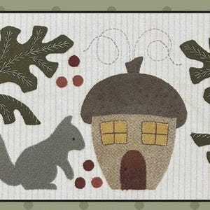 May include: A whimsical, rectangular, fabric art piece featuring a gray squirrel, an acorn-shaped house, and stylized leaves and berries. The color palette includes shades of gray, brown, green, and red, set against a cream-colored background with vertical stripes.