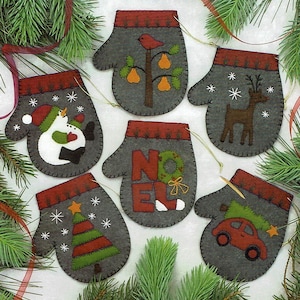 May include: Six felt Christmas ornaments shaped like mittens, each with a different design. The designs include a snowman, a Christmas tree, a car with a Christmas tree on top, a reindeer, a pear tree with a bird, and the word "NOEL".