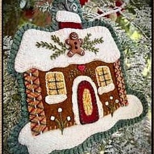 以下が含まれることがあります： ジンジャーブレッドマン、赤いドア、白い雪が付いたフェルトのジンジャーブレッドハウスのオーナメント。家は緑の葉と赤い煙突で飾られています。