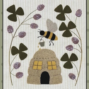 May include: A decorative textile panel featuring a whimsical bee carrying a bucket of honey towards a textured beehive. The design includes dark green clovers, purple flowers, and a light green background with vertical stripes.