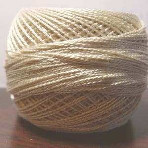 May include: A ball of off-white yarn, wound into a tight ball.