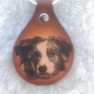 May include: A brown leather keychain with a silver key ring and an engraved image of a dog's face.