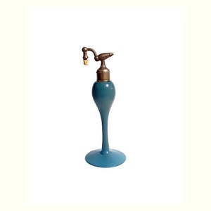 May include: A blue glass perfume bottle with a brass atomizer and a cork stopper. The bottle has a long, slender neck and a round base.