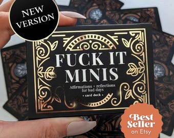 May include: A black card deck box with gold foil filigree borders and the white text FUCK IT MINIS, followed by the subtitle Affirmations + reflections for bad days, card deck. A black circular sticker reads NEW VERSION and an orange sticker reads Best Seller on Etsy.