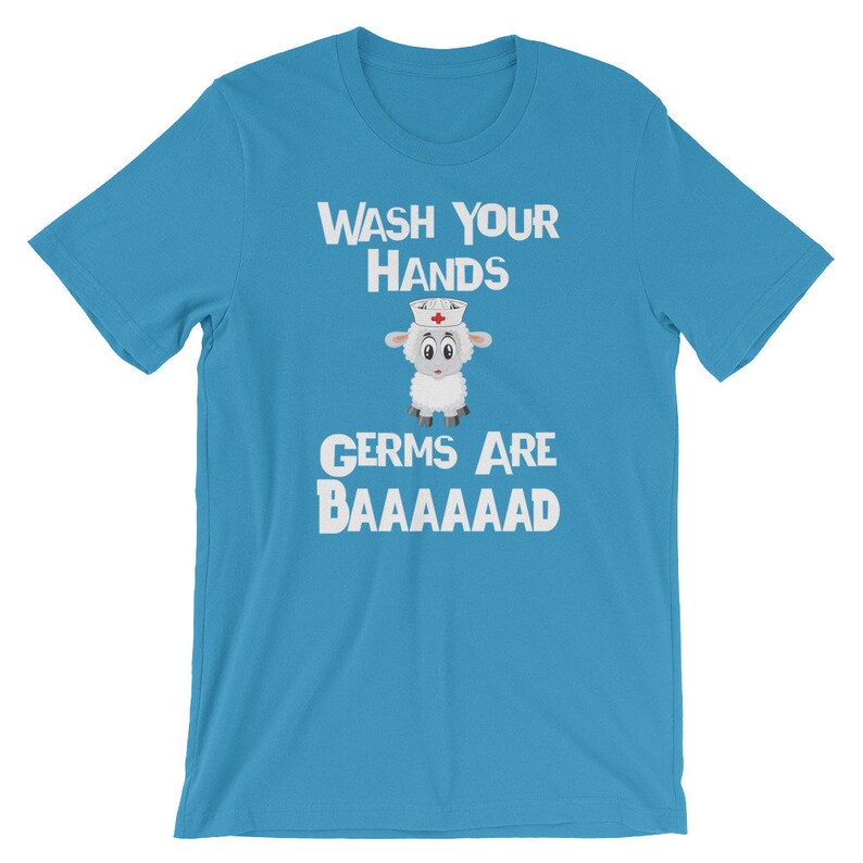 May include: A light blue t-shirt featuring a white sheep wearing a nurse's hat. The text "WASH YOUR HANDS GERMS ARE BAAAAAAAAD" is printed on the shirt.