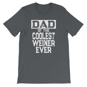 May include: Dark gray t-shirt with white text that reads "DAD OF THE COOLEST WEINER EVER".