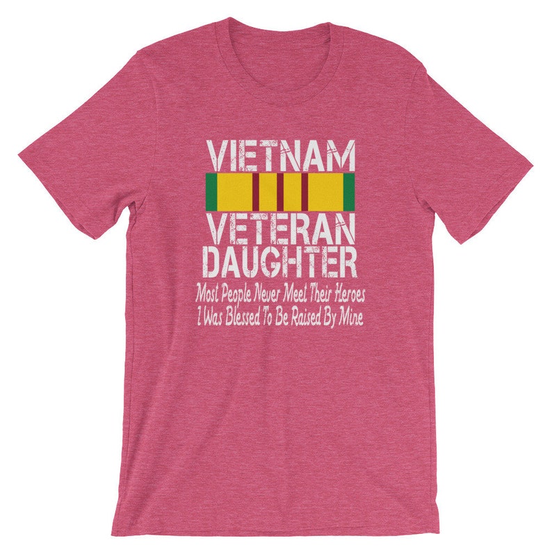 May include: A pink t-shirt with the text "VIETNAM VETERAN DAUGHTER" and a yellow and green ribbon. The text below the ribbon reads "Most People Never Meet Their Heroes I Was Blessed To Be Raised By Mine."