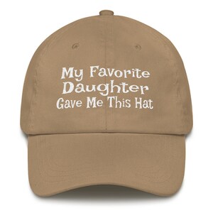 May include: A tan baseball cap with white embroidery that reads "My Favourite Daughter Gave Me This Hat".