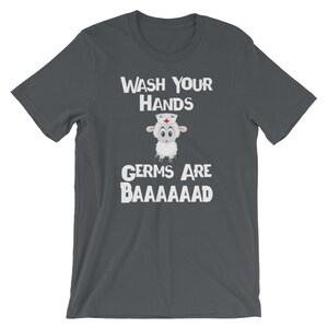 May include: Dark grey t-shirt with a white graphic of a sheep wearing a nurse's hat. The text "WASH YOUR HANDS GERMS ARE BAAAAAAAAD" is printed on the shirt.