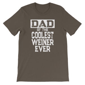 May include: A dark brown t-shirt with white text that reads "DAD OF THE COOLEST WEINER EVER".
