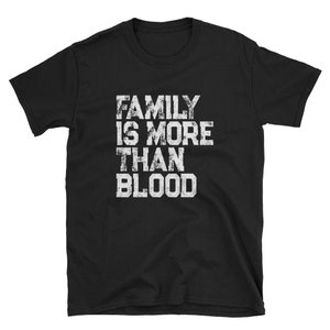 May include: Black t-shirt with white text that reads "Family is more than blood."
