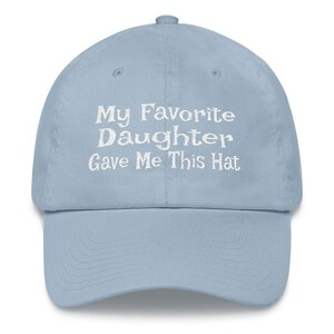 May include: A light blue baseball cap with white embroidered text that reads "My Favourite Daughter Gave Me This Hat".